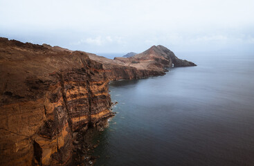 Dramatic volcanic cliffs and serene ocean view at Ponta de S&atilde;o Louren&ccedil;o, Madeira Island, Portugal &ndash; panoramic coastal landscape with sailboats, hiking trails, and wild natural beauty.