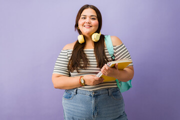 Smiling plus-size student carrying books and backpack