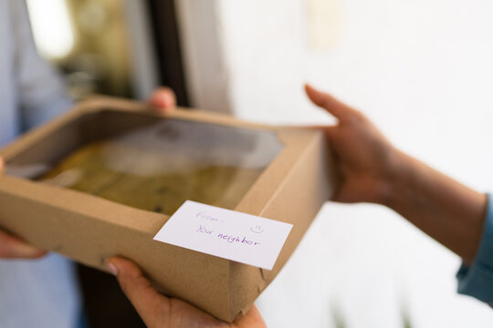 Neighbor receiving homemade dessert box with from your neighbor note, expressing kindness and community