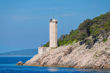 Scenic coastal lighthouse on rocky cliff under clear blue sky