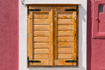 Rustic wooden shutters on vibrant red and white wall