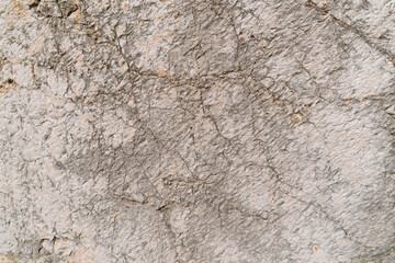 Close-up of rough gray concrete wall texture with cracks