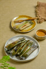 Grilled otak-otak or wrapped fish cake. traditional Indonesian food. Seved with peanut sauce