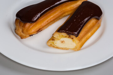 Eclairs with custard and chocolate glaze on plate close-up