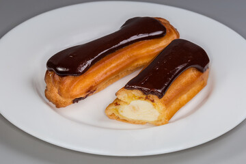 Eclairs with custard and chocolate glaze on plate close-up