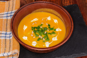 Serving of lentil pumpkin soup puree on rustic table