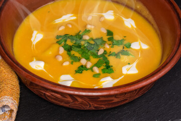 Hot lentil pumpkin soup puree in clay bowl, close-up