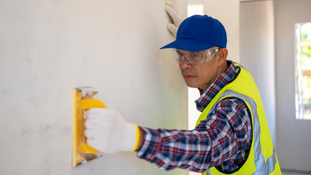 Construction worker applying finishing touches residential interior photography indoors close-up home improvement concept