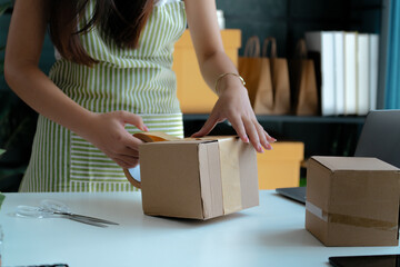 An SME owner prepares small box for online retail logistics and shipment