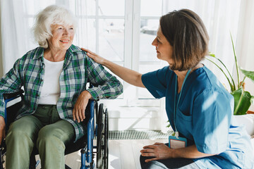 Side view of friendly caregiver or nurse in blue uniform getting acquainted with patient in...