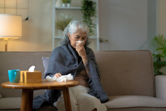 A senior woman stays cozy at home recovering from flu fever in winter season
