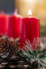 Bright red candles surrounded by pinecones and greenery create a cozy holiday atmosphere in a warm setting