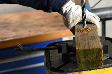 Close-up of drill press boring a hole in wooden beam in workshop