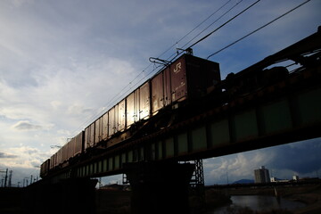 夕日を反射して疾走するコンテナ貨物列車のイメージ