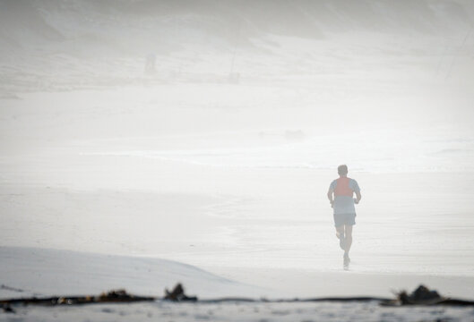 man running on the beach surrounded by fog or mist early morning concept sport, fitness, jogging, lifestyle with copy space