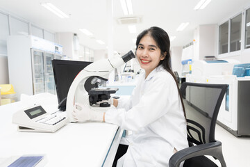 Selective focus woman Asian scientist using microscope to analyze blood smear slide sample at labolatory room.Specialist development and production of new medicines.