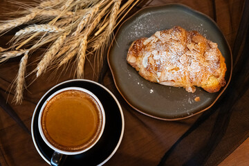 Close up delicious breakfast menu croissant and coffee cup on the wood table in the restaurant.