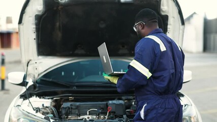 African mechanic using a laptop to run diagnostics on a car engine, troubleshoot issues, and monitor vehicle performance in his workshop - Powered by Adobe