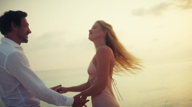 A romantic couple embraces and kisses on a stunning tropical beach during a golden sunset. They enjoy their luxurious vacation, filled with love and happy moments together by the ocean.