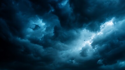 Dark swirling storm clouds gather in a dramatic sky as faint light breaks through the ominous layers creating a powerful weather spectacle