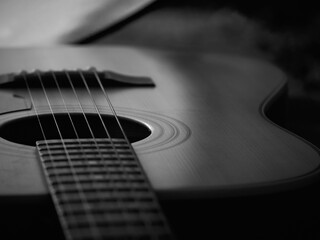 Monochrome photo of guitar with neck extending left, few frets in focus, rest of instrument softly blurred, light highlighting center and upper body, right side out 