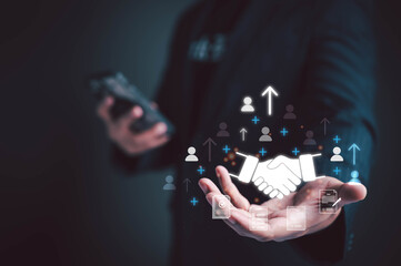 Businessman holding digital handshake icon with human network and upward arrows. Concept of business partnership, teamwork, employee growth, HR management, and successful collaboration.
