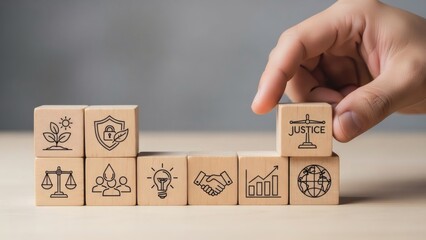Corporate ethics and sustainable business. Hand positioning justice icon on tiered wooden blocks showing growth, security, teamwork, and global responsibility.
