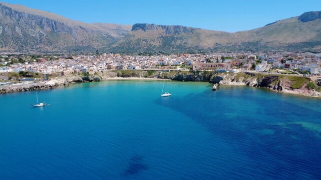 Sailboats Glide Through Clear Waters Near a Charming Coastal Town Under Bright Blue Skies. Terrasini, Sicily, Italy