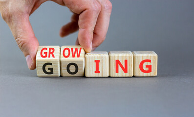 Going and growing symbol. Concept words Going Growing on beautiful wooden blocks. Beautiful grey background. Businessman's hand. Business going and growing concept. Copy space.