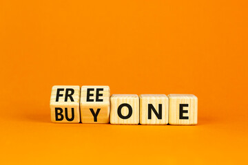 Buy and free one symbol. Turned wooden cubes and changed words Buy one to Free one. Beautiful orange table orange background, copy space. Business Buy and free one concept.