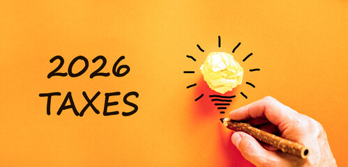 2026 taxes new year symbol. Concept words 2026 taxes on beautiful orange paper. Beautiful orange paper background. Businessman's hand with pen. Business and 2026 taxes new year concept. Copy space.