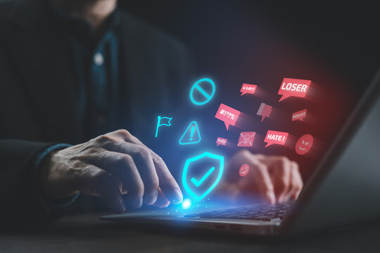 A user activates a digital shield on a laptop to block toxic online messages, cyberbullying prevention, digital safety, online protection, and awareness against harmful social media behavior.