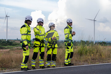 Engineers inspect wind turbine site on a clear day with wind turbines in the background