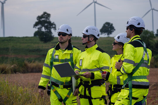 Wind energy team conducts inspection and planning at wind farm in broad daylight with turbines in the background