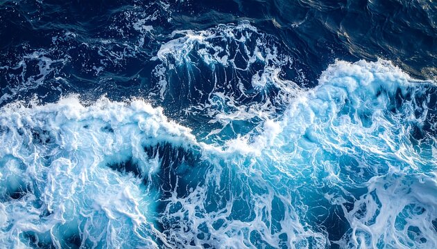 Aerial ocean view featuring a foamy white wave cresting against dark blue depths of the water - Powered by Adobe