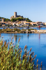 Fototapeta premium Village of Gruissan by the lagoon under the Barberousse Tower with cyclists in the foreground