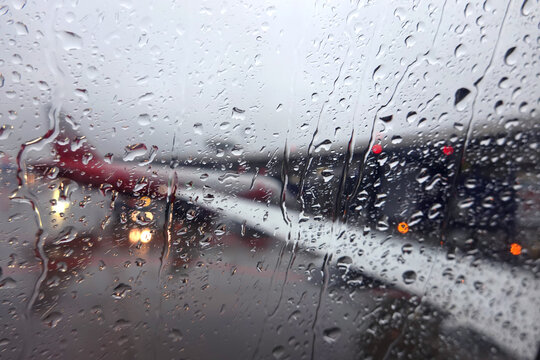 Blurred window view to air field with aircraft silhouettes through wet glass in the overcast weather in the evening
