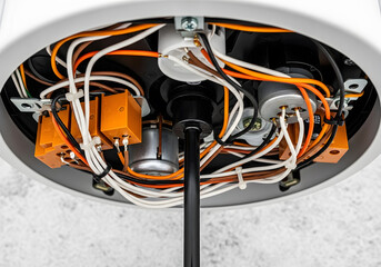 Close up of complex electrical wiring and internal circuitry | Orange plastic relays and multicolored cables inside device housing | Detailed view of electronic components connection and assembly 