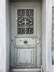 Old weathered wooden door with peeling paint and ornate metal lattice. Vintage rustic entrance with distressed textures, aged details, and a historic atmosphere suitable for backgrounds or architectur