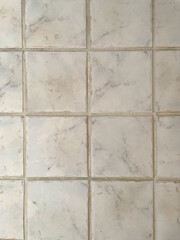 Light ceramic tile texture with a subtle marble pattern. Beige and gray tones, natural grout lines, stone surface. High-resolution background for interior design, flooring, and architecture projects.