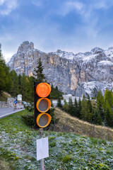 A red stop traffic light on a forest road in the mountains. Vertical photo.