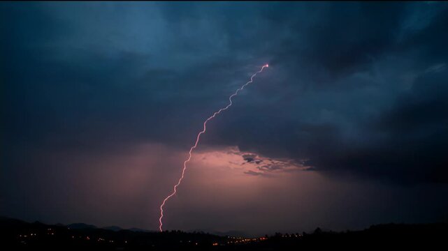 Dramatic lightning strike illuminates the dark stormy sky over a silhouetted landscape with distant town lights