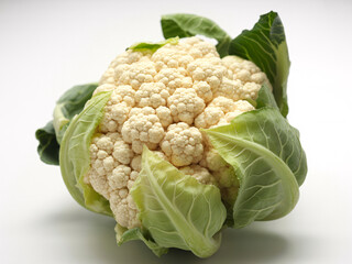 Fresh cauliflower head surrounded by vibrant green leaves, perfect for healthy recipes and culinary creations, promoting wellness and mindful eating today