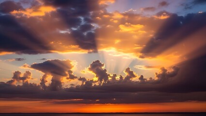 Golden sunbeams pierce dramatic clouds over the ocean at sunset