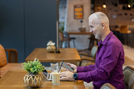 Senior man telecommuting at cafe enjoying digital work