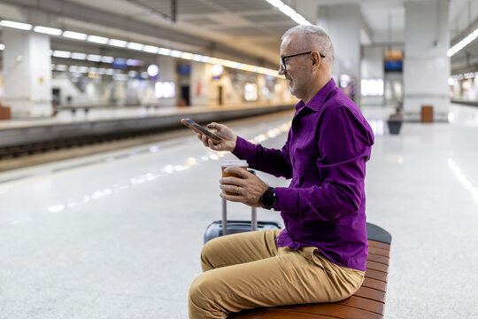 Mature man checking smartphone at train station