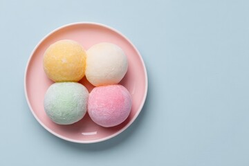 Pink bowl containing three colorful bath bombs in various shapes and sizes for relaxation