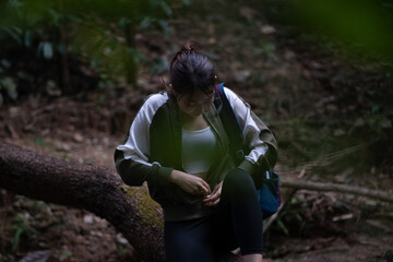 A woman is sitting on a tree trunk in the woods