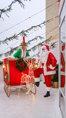 Santa Claus and elf pose with a reindeer sleigh for Christmas