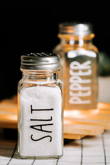 Salt and pepper shakers placed on a wooden surface in a cozy kitchen setting